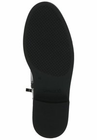 Semelle de chaussure noire avec une surface texturée et une forme arrondie. Inclut un marquage et une finition lisse près du talon pour la prise et le confort.