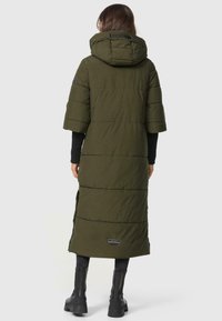 Pitkä oliivinvihreä toppatakki, jossa on huppu, lyhyet hihat ja sivurei'ät. Ominaisuuksiin kuuluu ommeltu kuvio ja logopainatus helman kohdalla.