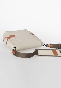 Beige crossbodytas gemaakt van zachte stof, met bruine leren accenten, verstelbare riem, rechthoekige vorm en eenvoudige stiksel details.
