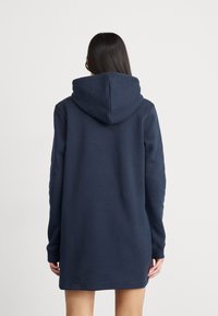 Navy blue hooded sweatshirt dress with long sleeves, a kangaroo pocket, ribbed cuffs, and a relaxed fit, made of smooth, soft fabric.