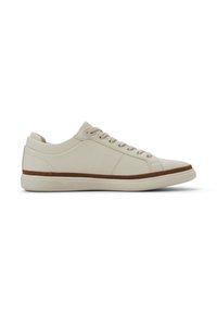 Zapatillas de deporte de cuero beige con un acabado texturizado, puntera redonda y acentos en marrón claro a lo largo de la entresuela. Presentan cordones planos y un collar acolchado.