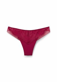 String rouge avec des détails en dentelle à l'avant et des accents en maille transparente. Tissu lisse avec une coupe taille basse et une couverture minimale à l'arrière.