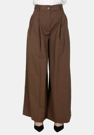Pantaloni marroni a vita alta e gamba larga con pieghe, indossati con tacchi neri con punta a mandorla e un top bianco infilato.