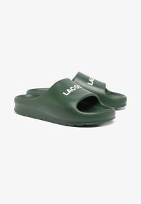 Infradito in plastica verde con punta aperta, dotate di suola testurizzata e logo bianco "LACOSTE" sulla fascia anteriore.