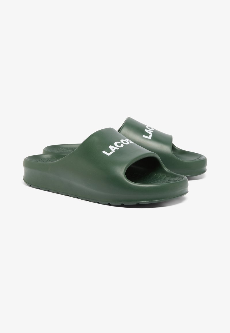 Grüne Kunststoff-Sandalen mit offener Zehe, ausgestattet mit einer strukturierten Sohle und dem weißen "LACOSTE"-Logo auf dem vorderen Riemen.