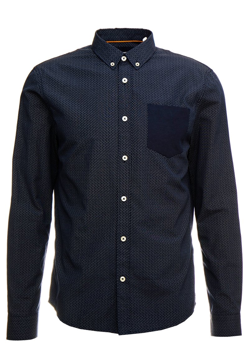 Camicia a maniche lunghe blu navy con un piccolo motivo a pois bianchi, colletto alla francese e una tasca a toppa scura sul lato sinistro del petto. Bottoni bianchi.