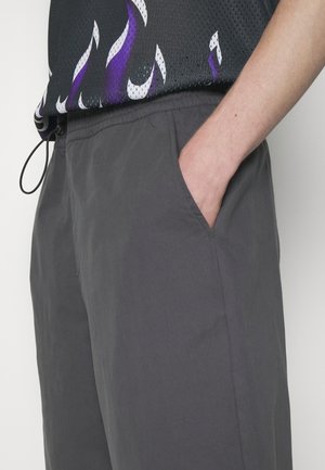 Graue Shorts aus leichtem Stoff, mit Seitentaschen und einem elastischen Bund mit Kordelzug. Glatte Textur und schlichtes Design.