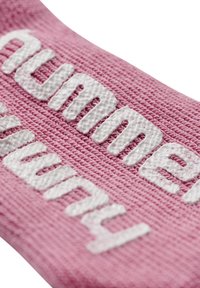 Rosa Textil mit erhabenerweißer Schrift. Das Material hat eine strukturierte Webart und zeigt die Worte in einer fetten, modernen Schriftart.