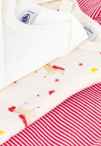 Drei Baumwoll-Babykleidungstücke: eines in Weiß, eines in Creme mit einem Pferde- und Sternmuster in Rot und eines mit roten Streifen. Soft und leichtes Material.