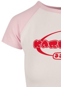 Short-sleeve t-shirt featuring a white body with light pink raglan sleeves, red logo and text across the chest, made of smooth cotton material.
