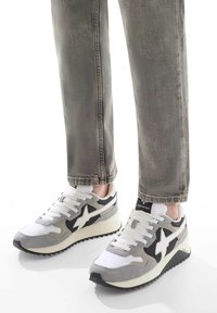 Sneakers sportivi che presentano una combinazione di rete bianca e suede grigio, con accenti neri e una suola in gomma testurizzata per una migliore aderenza.