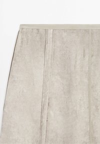 Jupe en daim beige avec des panneaux verticaux cousus et une taille simple, posée à plat sur un fond blanc.
