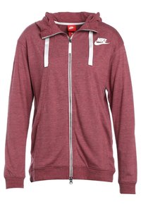 Red zip-up hoodie featuring a white Nike logo, adjustable drawstrings, and ribbed cuffs. Made of soft, textured fabric.