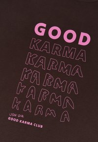 Tela negra con texto rosa atrevido y contorneado: "BUENO" en la parte superior, varias iteraciones de "KARMA" debajo y "ÚNETE A NUESTRO CLUB DE BUENA KARMA" en la parte inferior.