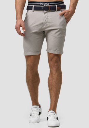 Light gray shorts made of cotton, featuring a rolled hem, front pockets, and contrasting dark waistband with a woven belt. Paired with white sneakers.
