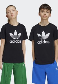 T-shirts noirs avec le logo Adidas blanc, associés à des pantalons de sport verts et bleus. Le design présente un col rond classique et une coupe décontractée.