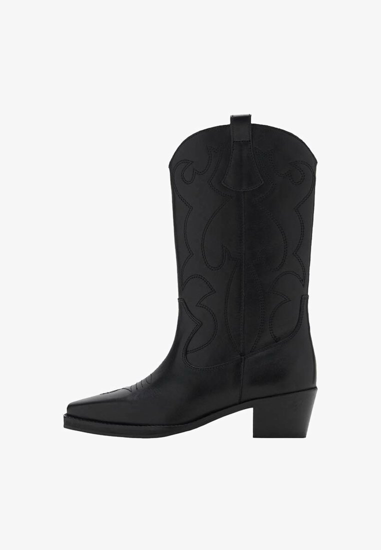 Bota de vaquero de cuero negro con patrones decorativos bordados, punta afilada y tacón bajo cuadrado, vista lateral sobre fondo blanco.