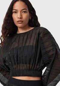 Zwarte geplooide cropped blouse van doorschijnende stof, met elastische taille en brede mouwen. De textuur is soepel met een gelaagd ontwerp.