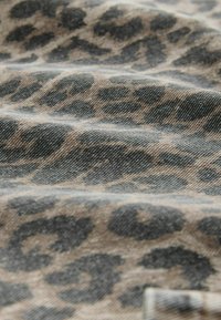 Leopardenmuster-Denimstoff mit einer strukturierten Oberfläche in Schattierungen von Braun und Grau, versehen mit kühnen, unregelmäßig geformten Mustern.