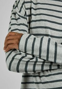 Graues Langarmshirt mit dunklen grauen horizontalen Streifen. Verfügt über einen lässigen Schnitt, sichtbare Nähte und eine weiche Stofftextur.