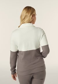 Pullover in pile caratterizzato da un design a colori misti: metà superiore bianca, metà inferiore marrone. Morbido al tatto, con maniche lunghe e colletto.