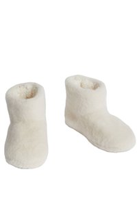 Botas de casa blancas y suaves con una textura esponjosa y un diseño de punta redondeada. De altura hasta el tobillo con una abertura lisa y sin herrajes visibles.