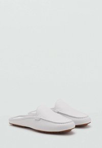 Scarpe slip-on bianche realizzate in pelle liscia, con tomaia cucita, punta rotonda e suola in gomma marrone chiaro. Design minimalista.