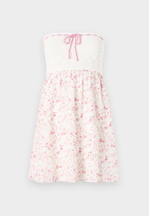 Bezplecu ziedu kleita ar baltu tamborētu korpusu un rozā saišu detaļām, kā arī vieglu svārku ar rozā ziedu rakstiem uz gaiša fona.