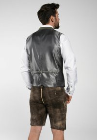 Grau gemusterte Weste mit glatter Textur, kombiniert mit braunen Shorts mit Seitentaschen und kontrastierenden Nähten. Darunter ein weißes Hemd.