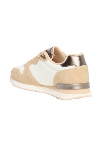Zapatilla deportiva en beige y blanco con parte superior de malla texturizada, acentos de ante, talón metálico y suela de goma en contraste.