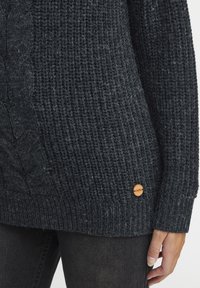 Donkergrijze gebreide trui met een gestructureerd ribpatroon, voorzien van een opvallend kabelpatroon en een houten logo-accent aan de zijkant.