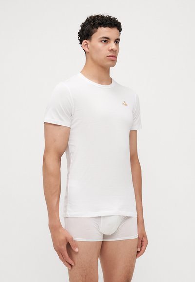 Tricou alb cu mânecă scurtă, fabricat dintr-un material moale, având un mic logo auriu pe piept. Purtați cu chiloți albi subțiri.