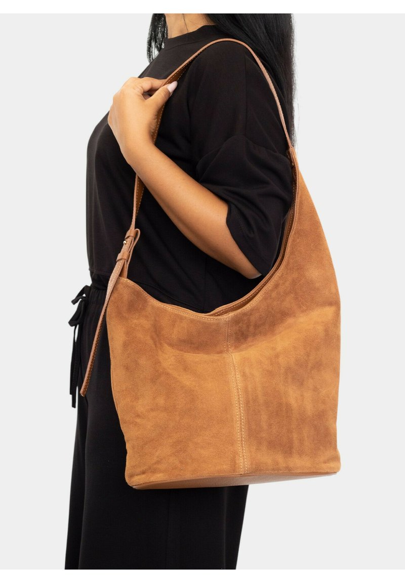 Bolso hobo de ante marrón con una parte superior curvada, correa ajustable y una textura suave. Presenta una base plana para estabilidad al apoyarlo.