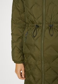 Chaqueta acolchada verde oliva con cremallera frontal, puños elásticos, cuerdas ajustables en la cintura y bolsillo con cremallera en el lado izquierdo.