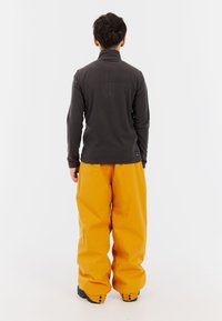 Grijze langemouw top met een hoge kraag en oranje baggy broek. De broek heeft een gladde textuur en de top is gemaakt van een zacht materiaal.