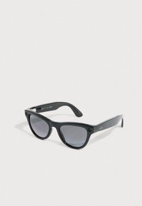 Occhiali da sole Ray-Ban Wayfarer neri con lenti scure appoggiati su una superficie bianca inclinati.