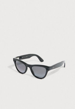 Black Ray-Ban Wayfarer sunglasses with dark tinted lenses resting on a white surface at an angle.
