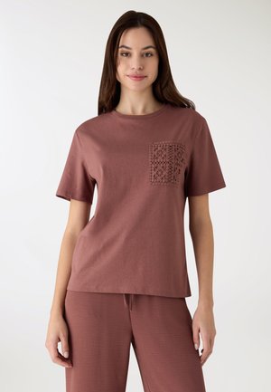 T-shirt a maniche corte e girocollo in cotone color rosso-marrone tenue, con una tasca in pizzo lavorato a sinistra. Abbinata a pantaloni coordinati.
