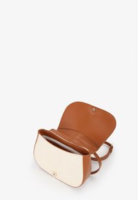 Bolso cruzado de cuero marrón claro con un frente de lona crema. Cuenta con un cierre de solapa superior y un bolsillo interior. Textura suave y hardware mínimo.