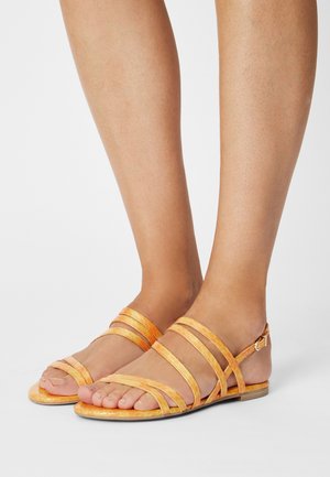 Orange strappy sandals with multiple wide bands, flat sole, and ankle buckle, featuring a glossy finish and open-toe design.