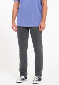 Vaqueros grises con corte slim y una textura sutil, combinados con una camiseta azul clara y zapatillas negras con cordones blancos.