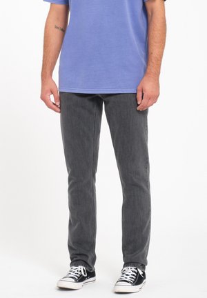 Gray jeans with a slim fit and subtle texture, paired with a light blue T-shirt and black sneakers featuring white laces.