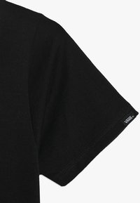 Černé bavlněné tričko s kulatým výstřihem a krátkými rukávy. Má šitý lem a malé bílé logo Vans na rukávu.