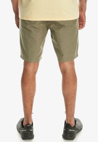 Olivenfarvede shorts lavet af strukturstof, med almindelig pasform og opsmøgte cuffs, parret med sorte sportsko.