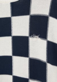 Temno modra in bela pletena tkanina z vzorcem šahovnice in majhnim vezenim logotipom v obliki pisave na enem temnem kvadratu.