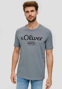 Gray crew-neck t-shirt made of soft fabric, featuring a prominent black print: "s.Oliver Elevate Essentials Since 1969." Short sleeves.