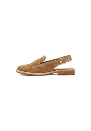 Mocasín marrón de ante con tiras traseras, detalles cosidos, suela plana y correa ajustable con hebilla sobre fondo blanco.