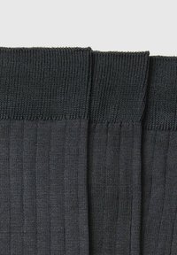 Calze a costine grigie scure con una morbida texture a maglia, dotate di un risvolto elasticizzato nella parte superiore. Il tessuto presenta dettagli a costine uniformi.