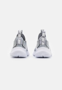 Baskets de sport grises avec un dessus texturé, un talon renforcé et une semelle en caoutchouc blanc. Présente un tirant gris proéminent avec le lettrage de la marque.