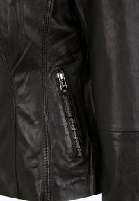 Sort læderjakke med en tekstureret overflade. Har en sidelomme med lynlås og glatte sømme, som fremhæver et skræddersyet design.